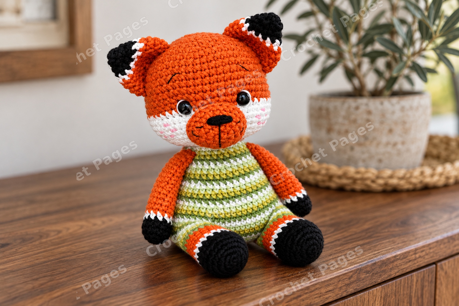 Crocheted fox cub with a green striped body and white muzzle.