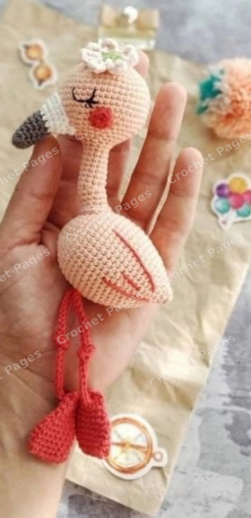 Crocheted flamingo with a long neck, flower detail and cord legs.