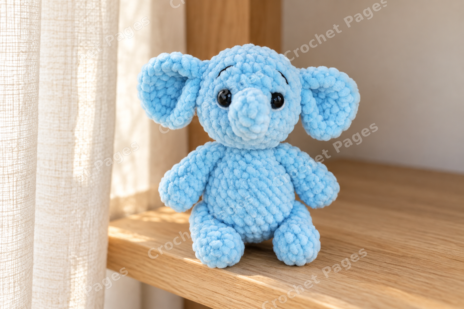 Small blue plush crochet elephant with large ears and a curled trunk.
