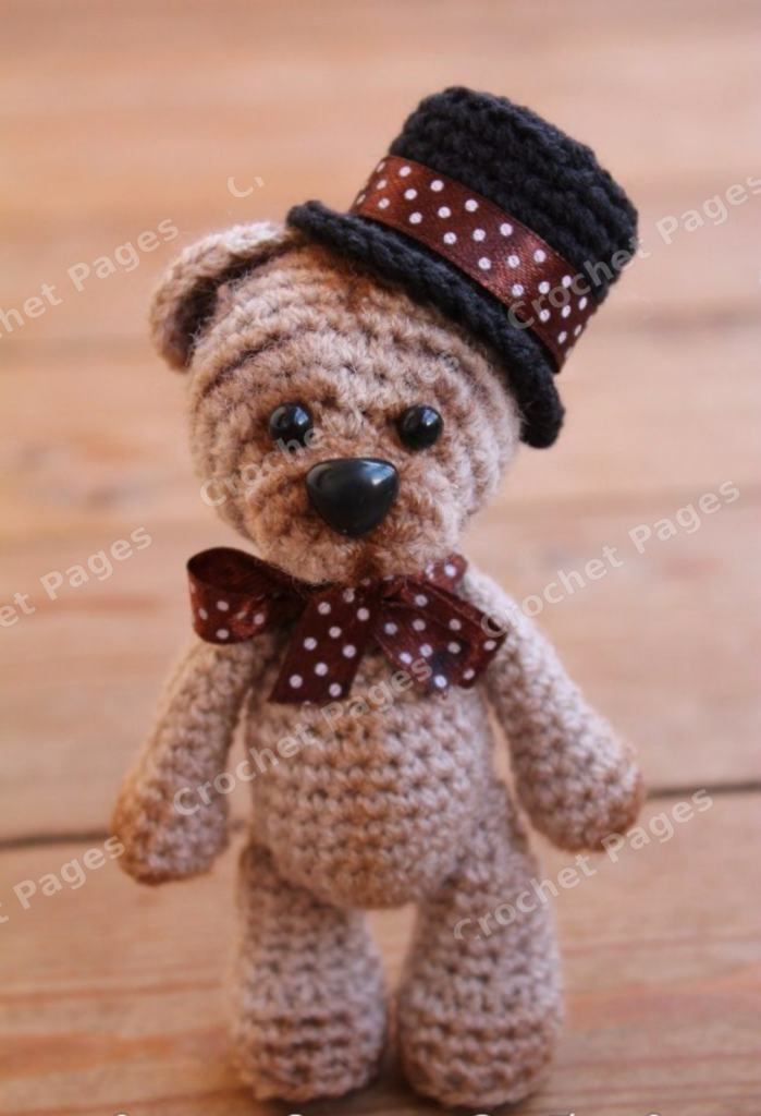Crochet a small teddy bear with a shaped muzzle, oval feet and a black top hat; finish with a ribbon bow. Finished-project view.