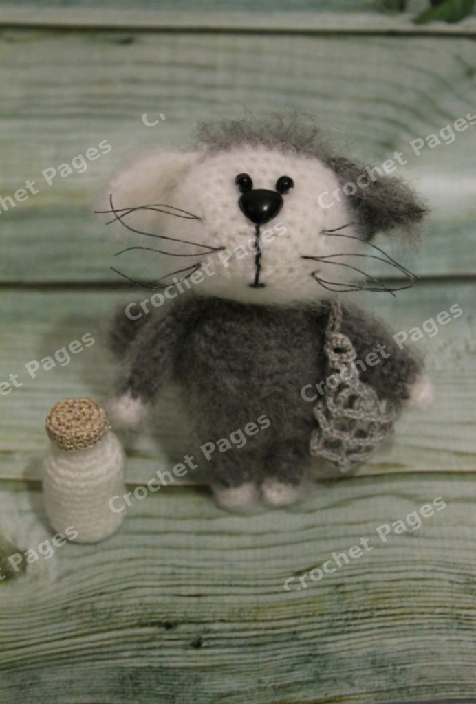 Make a fuzzy gray-and-white kitten with a contrasting muzzle and paws, triangular ears and a crocheted milk bottle. Finished-project view.