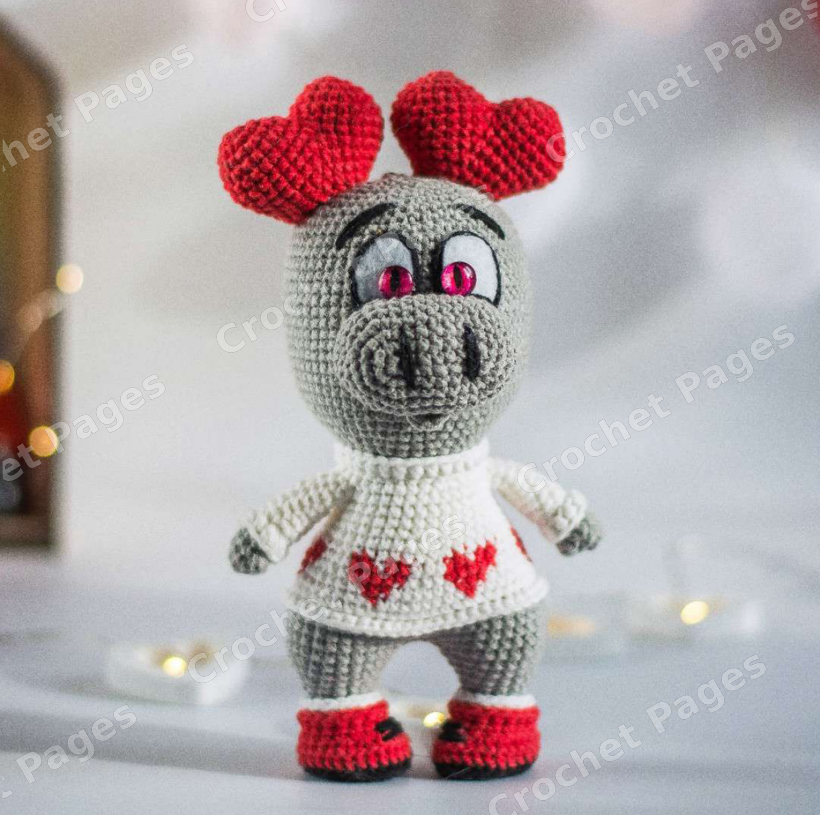Crochet a long-limbed love monster with a sculpted muzzle, contrasting paws and a red heart. Includes colorwork chart and construction photos. Finished-project view.