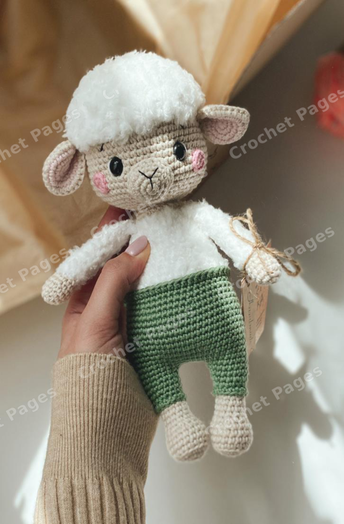 Make a long-eared sheep with fluffy fleece, embroidered facial details, pink cheeks and integrated green overalls with crocheted edging. Finished-project view.